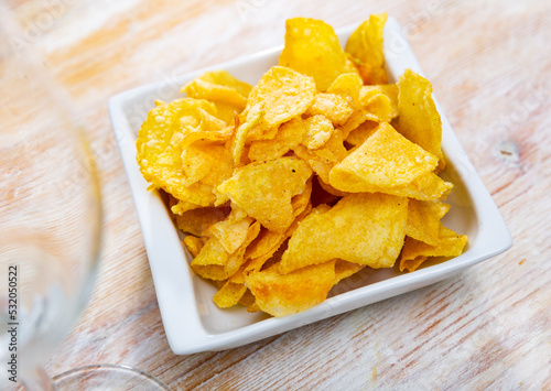 Plate of crispy deep-fried chips of thinly sliced natural potatoes. Popular vegetable snack..