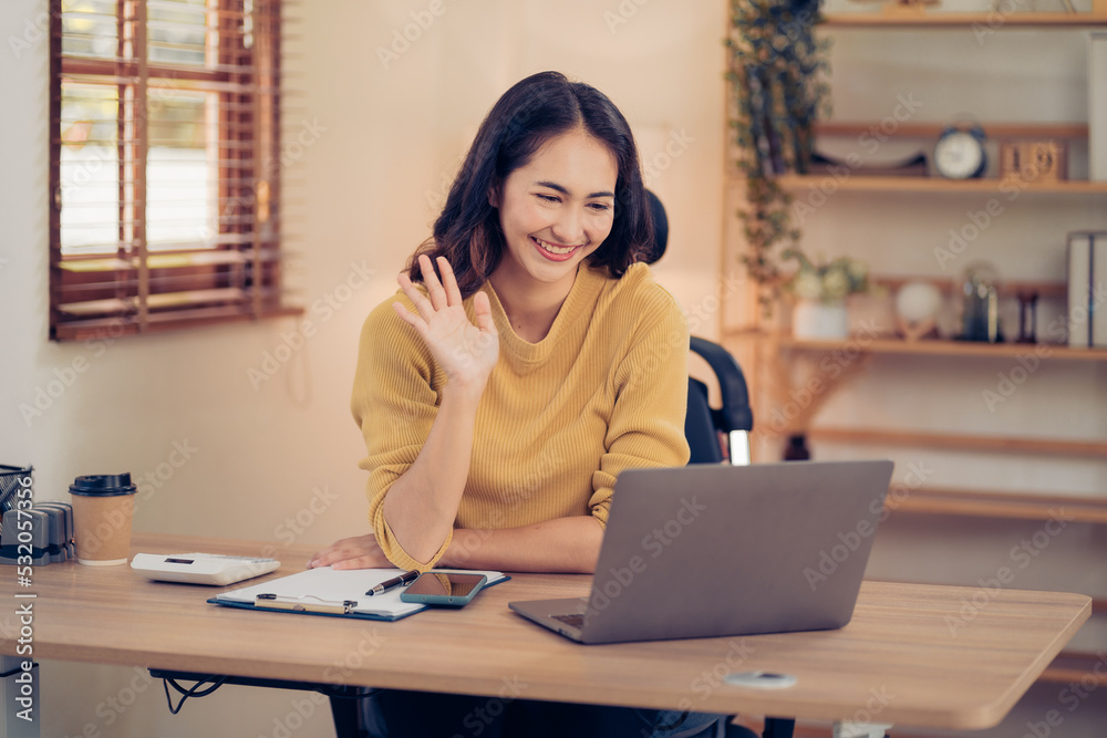 Portrait of a beautiful Asian woman looking at laptop screen while sitting at working desk in the office Portrait of a beautiful Asian woman looking at laptop screen while sitting at working desk in the office