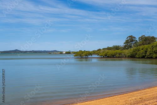 View from the shore past mangroves to the Redland Bay jetty and barge terminal, with Macleay and Stradbroke Islands in the distance. 