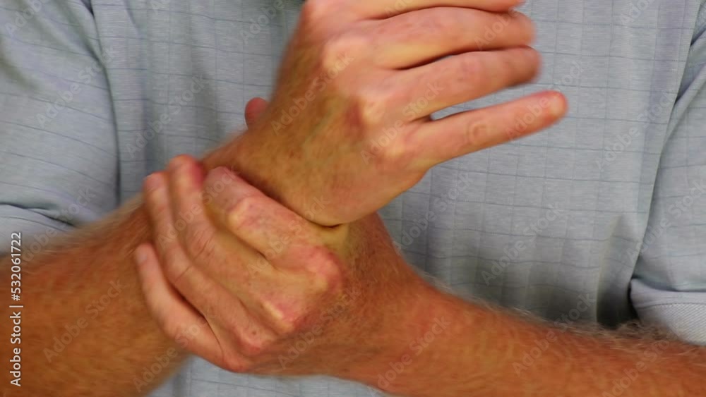Left hand of a mature caucasian man wearing a blue shirt self massaging his right wrist joint to help relieve pain. Right wrist-joint self-massaged to help pain by mature male in a blue shirt close-up Left hand of a mature caucasian man wearing a blue shirt self massaging his right wrist joint to help relieve pain. Right wrist-joint self-massaged to help pain by mature male in a blue shirt close-up