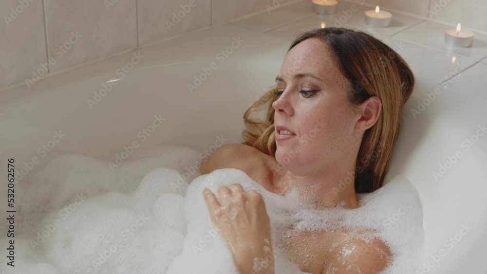 Close up of attractive woman moving foam with her hand while enjoying a nice bath