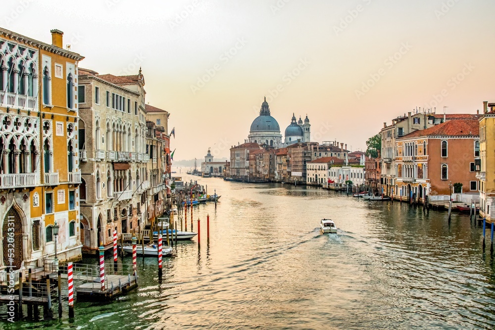 A boat at sunrise along the Grand Canal with  in Venice, Italy with Santa Maria della Salute, a Roman Catholic church and minor basilica in Venice, Italy