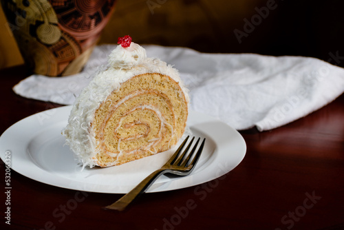 cake dessert covered with cream and grated coconut on a white plate on abstract background