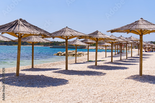 Fototapeta Naklejka Na Ścianę i Meble -  straw umbrellas on the beach. Empty beaches during quarantine. luxury beach. Pandemic warning, lack of tourists
