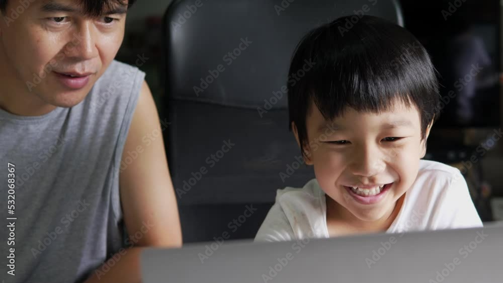 Authentic asian child boy using laptop with father. Kid smile with happy face looking to notebook for studying at home. Education learning, good family relationship, togetherness, home school concept. Authentic asian child boy using laptop with father. Kid smile with happy face looking to notebook for studying at home. Education learning, good family relationship, togetherness, home school concept.