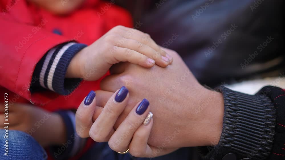 Close-up child hand touching woman palm in slow motion outdoors. Unrecognizable Caucasian son and young mother on backyard together. Family love and unity concept