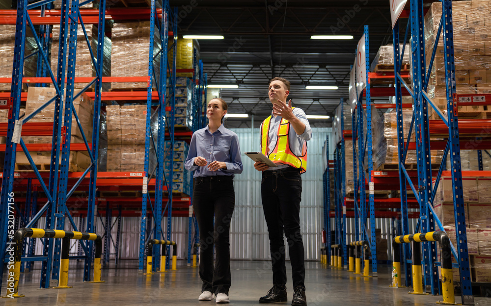Obraz premium Warehouse manager talking and pointing towards shelf while checking product in warehouse, Logistic industry concept.