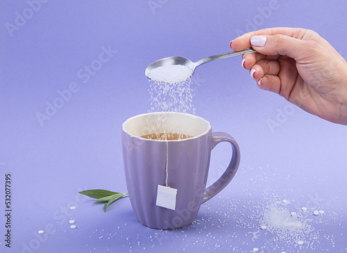 A cup of tea with sweetener and sugar.