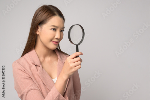 Young asian woman holding magnifying glass over white background, analysis and finance concept. .