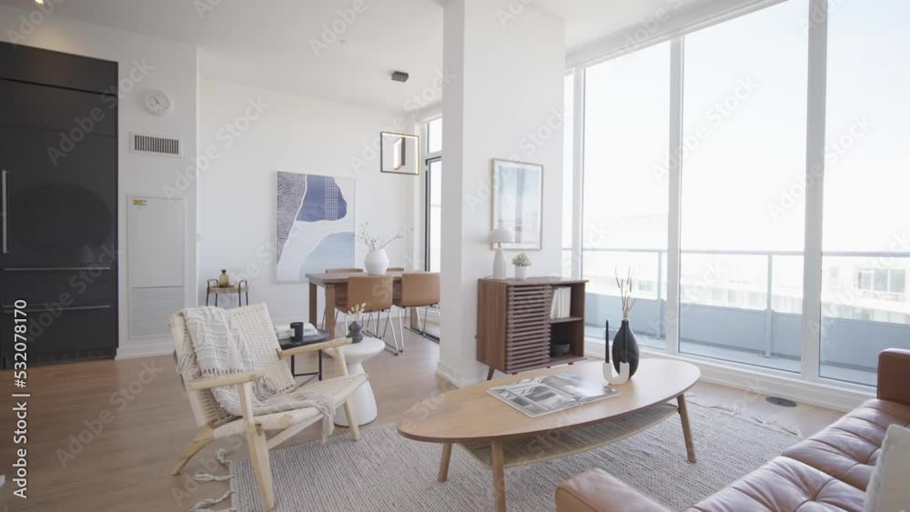 Wide angle push in shot No.2 showing the dinning and living area of a high ceiling penthouse condominium unit with a floor to ceiling window wall at the back and balcony outside during a sunny day Wide angle push in shot No.2 showing the dinning and living area of a high ceiling penthouse condominium unit with a floor to ceiling window wall at the back and balcony outside during a sunny day