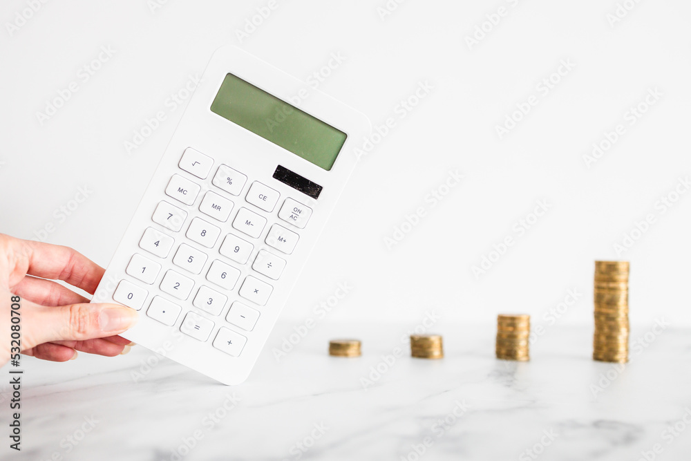 growing stacks of coins next to calculator representing increasingly expensive prices or savings and compound interests increasing, finance and money concept growing stacks of coins next to calculator representing increasingly expensive prices or savings and compound interests increasing, finance and money concept