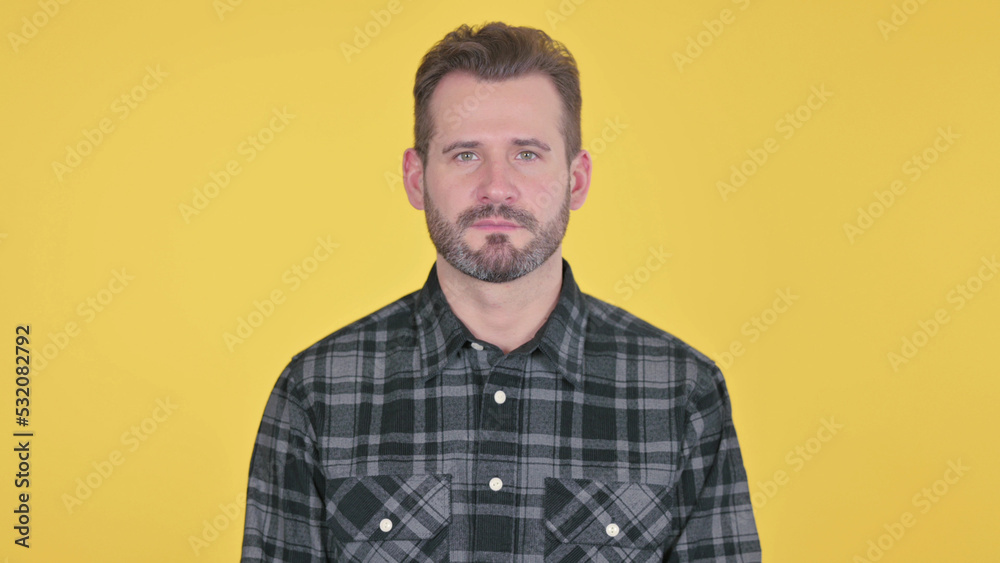 Serious Middle Aged Man Looking at the Camera, Yellow Background Serious Middle Aged Man Looking at the Camera, Yellow Background