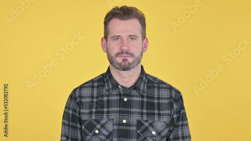 Serious Middle Aged Man Looking at the Camera, Yellow Background