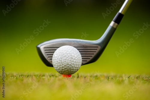 Golf clubs and golf balls on a green lawn in a beautiful golf course with morning sunshine