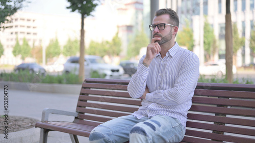 Pensive Young Adult Man Thinking while Sitting Outdoor on Bench