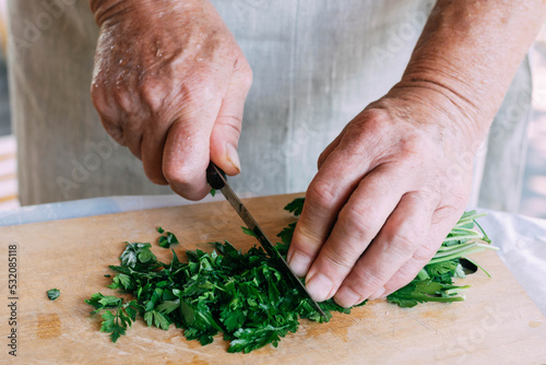 Female hands cuts fresh herbs for salad, soup or sauce preparation. Organic food, vegetarianism