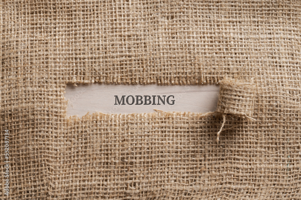 Rough linen fabric with a torn window in the middle with the word MOBBING written in it - obrazy, fototapety, plakaty 