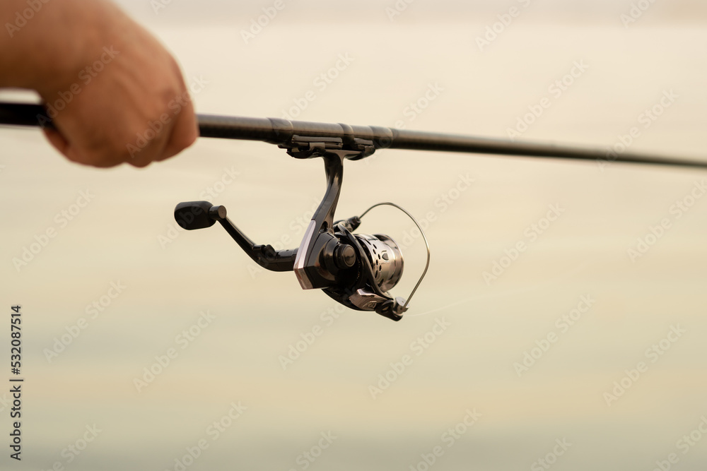 fisherman's hands holds spinning rod, rotates the coil handle. Hobby and activity fisherman's hands holds spinning rod, rotates the coil handle. Hobby and activity