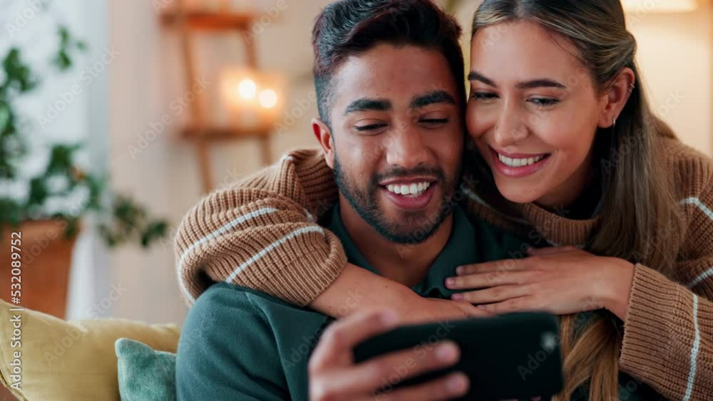 Love, relax and ecommerce couple on smartphone with hug embrace with kiss from girlfriend. Caring people in interracial and romantic relationship enjoy online shopping together in home. Love, relax and ecommerce couple on smartphone with hug embrace with kiss from girlfriend. Caring people in interracial and romantic relationship enjoy online shopping together in home.