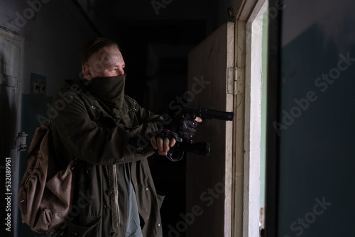 A post apocalypse soldier is walking in abandoned builder with a gun.