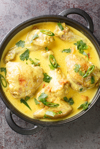 Kenyan Chicken in Coconut Sauce Kuku wa kupaka closeup in the plate on the table. Vertical top view from above