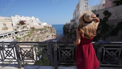 Traveling in Italy. Young tourist girl enjoying view of Lama Monachile in Polignano a mare, Apulia, Italy. Slow motion.