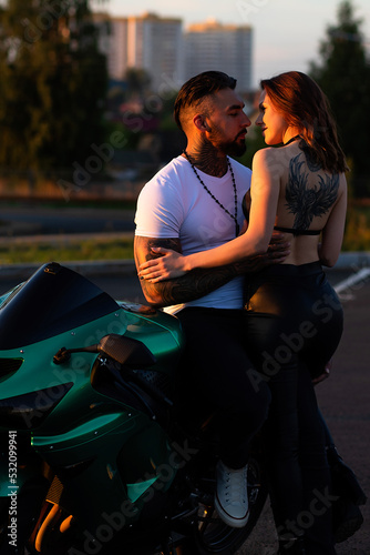 Couple hugging near motorbike at sunset