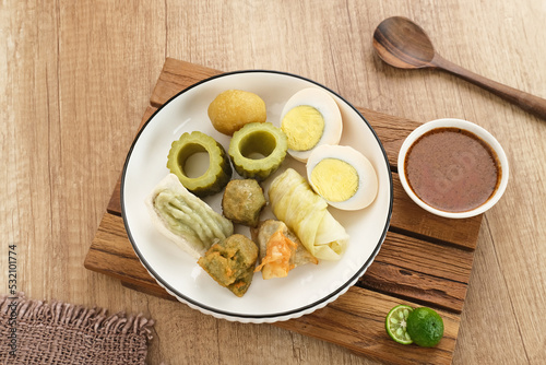 Siomay Bandung (Shumay) or steamed dumplings with boiled egg, tofu, potatoes and cabbage roll. Indonesian traditional street food with peanut sauce and soy sauce, served with green lime. 