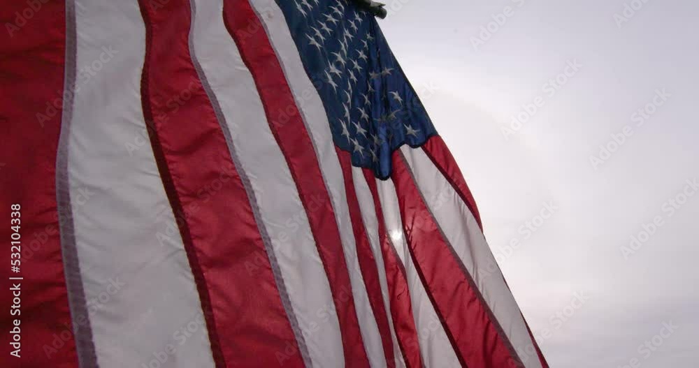 4k American Flag slowly blowing in the wind gentle breeze red white and blue Patriotic stars and stripes backlit B roll day