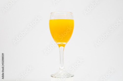 Orange juice in wine glass on white background
