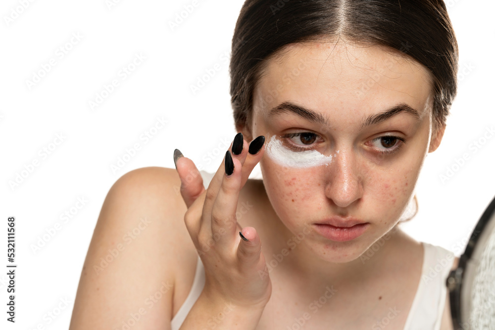young woman applyingvcosmetics product under the eye