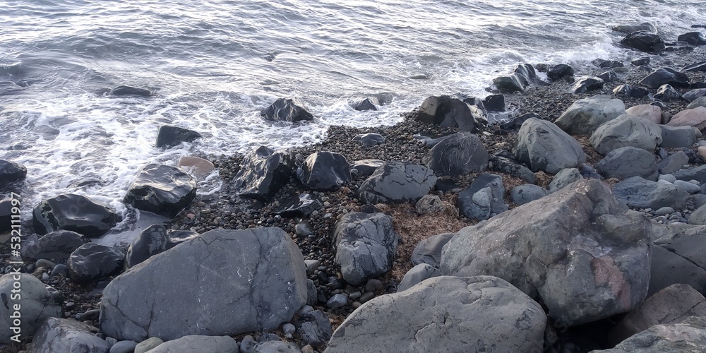 rocks next to the water on the beach of the sea