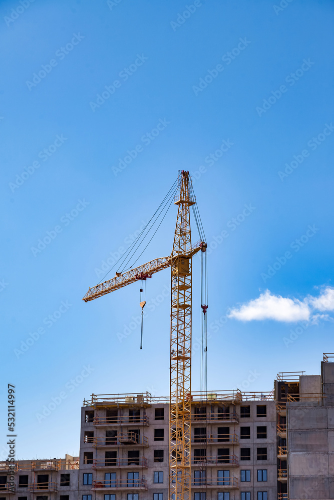 Creation site with construction crane work on against blue sky background. View of industrial cranes. Concept of construction of apartment buildings and renovation of housing. Copy text space