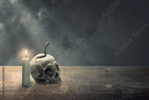 Fotografiet Human head skull on wooden table with centipede and candle