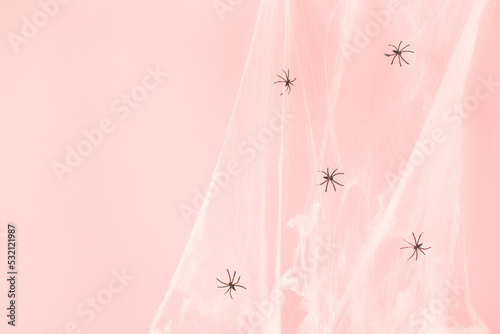 White spider web with black spiders on pastel pink background. Minimal pink Halooween concept.