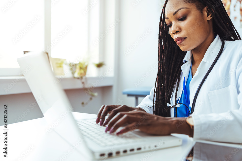 Woman watching a laptop screen while stretching her hand and typing on it. Doctor clicking on a laptop. Female doctor using laptop with mockup on screen for medical work at modern hospital office Woman watching a laptop screen while stretching her hand and typing on it. Doctor clicking on a laptop. Female doctor using laptop with mockup on screen for medical work at modern hospital office