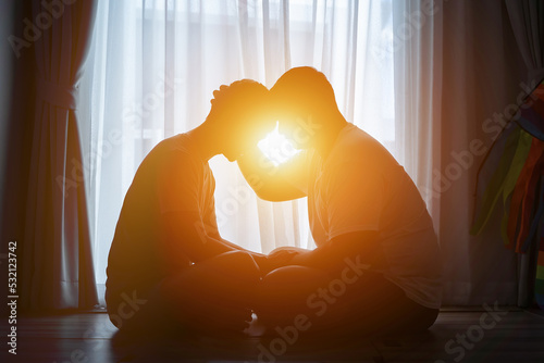 Two young men touching heads, hugging and looking at each other against sunset, silhouette of couple gay kissing in sunset photo