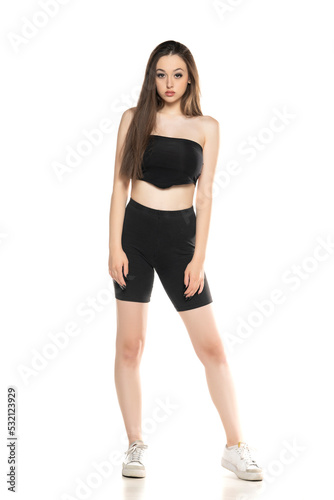 Young woman in black shorts and top posing in the studio