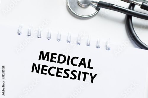 Fotografie Medical Necessity text on a notebook on a light desk next to it is a stethoscope