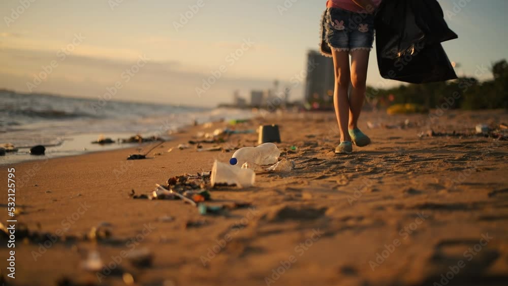 Woman under picking up plastic bottle garbage environment pollution cleaning up on the beach is volunteer concept with sunset sky background.