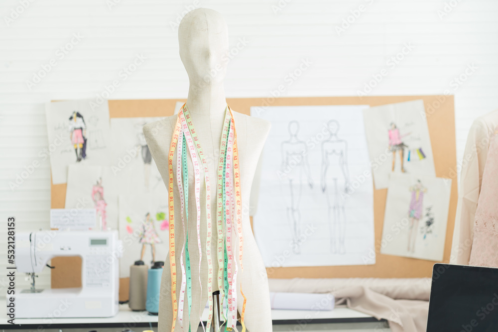 Obraz premium Dummy mannequin with hanging measuring tape with fashion design background in the tailor shop. garment, design, fashion, dressmaking concept