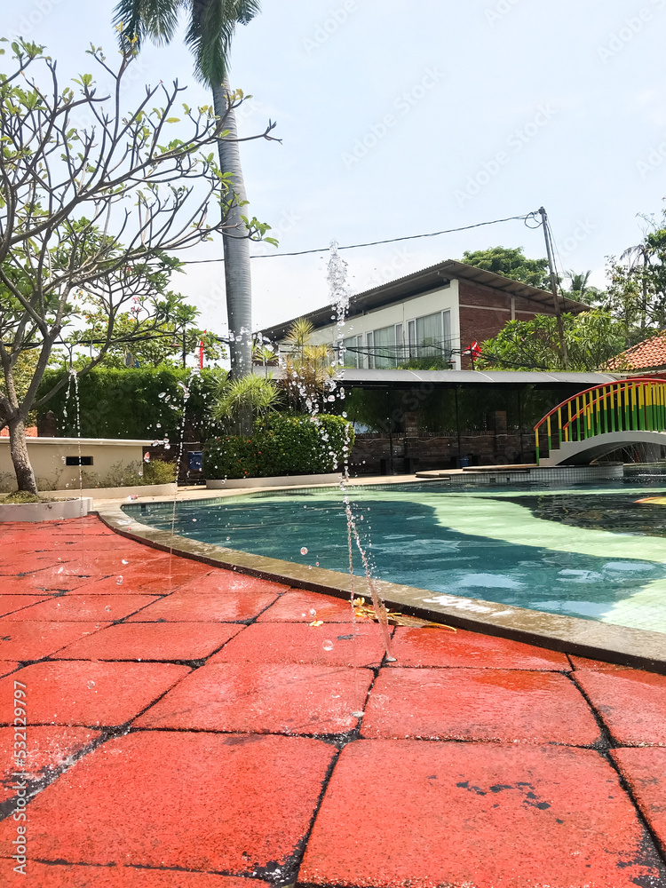 Semarang, Indonesia. 2022. Small fountain near the swimming pool on a red background