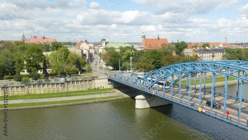 Fixed Aerial View of City Tram Driving over Blue Jozef Pilsudski Bridge. Krakow photo