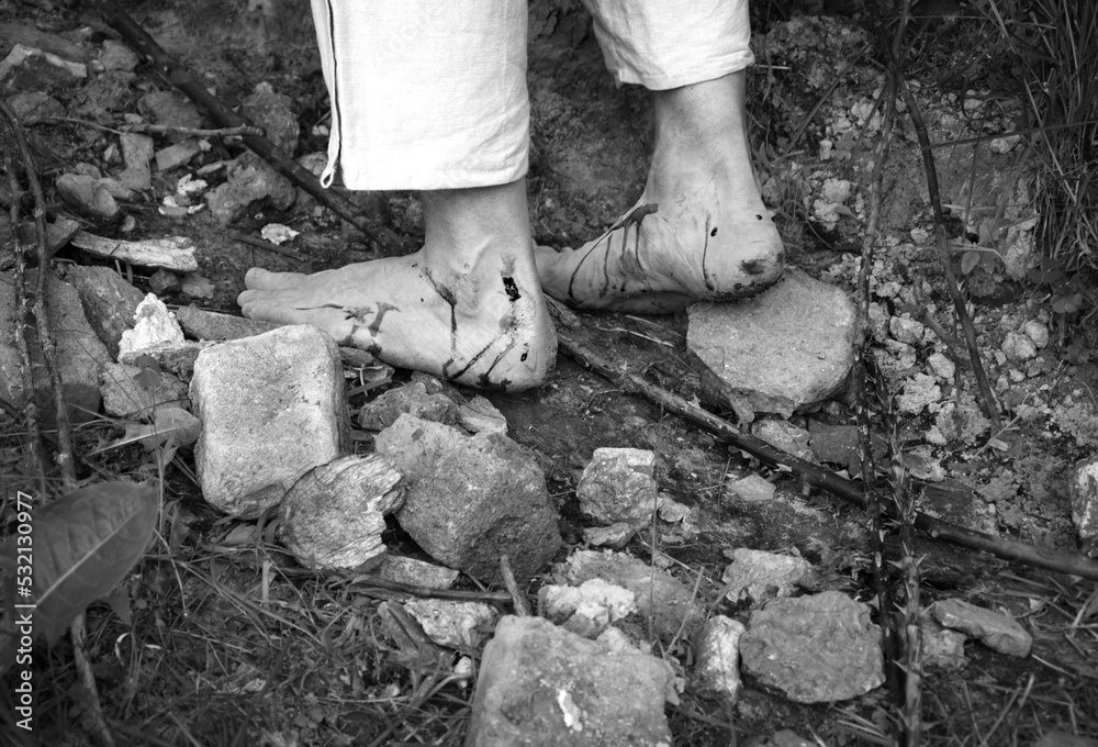 Fototapeta premium Wounded feet walk a hard rocky path