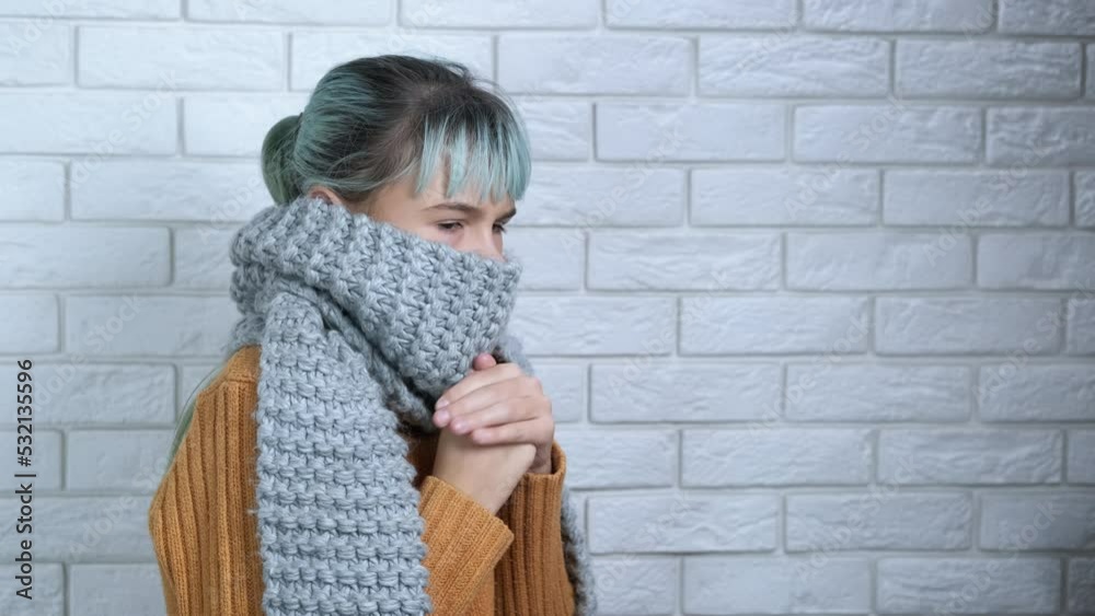 Warming up in scarf in the cold apartment. A stressed teen warming up with woolen scarf in unheated room during winter crisis. Warming up in scarf in the cold apartment. A stressed teen warming up with woolen scarf in unheated room during winter crisis.