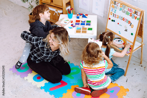 Teacher with children having fun and playing games, learning letters and numbers in kid development childcare center 
