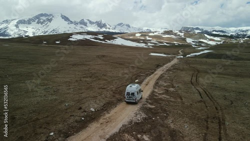 Aerial slowly follows camper van on dirt road in mountains, Montenegro. photo