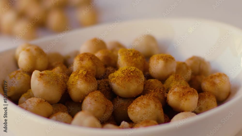 Turmeric rain falls in slow motion on chickpeas placed in a white bowl Turmeric rain falls in slow motion on chickpeas placed in a white bowl