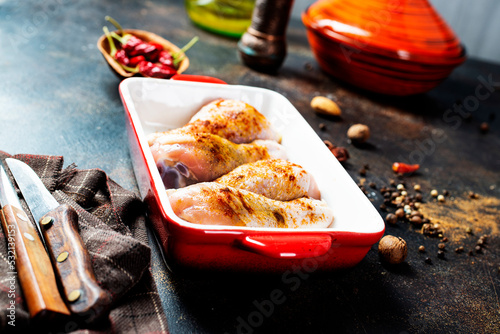 Raw uncooked chicken legs, drumsticks in bowl, meat with ingredients for cooking