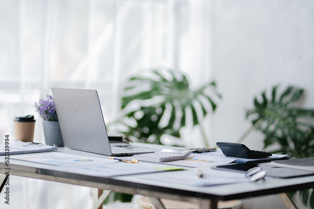 Empty workspace, no people, office desk, with laptop, calculator, graphs, documents on the table. Empty workspace, no people, office desk, with laptop, calculator, graphs, documents on the table.